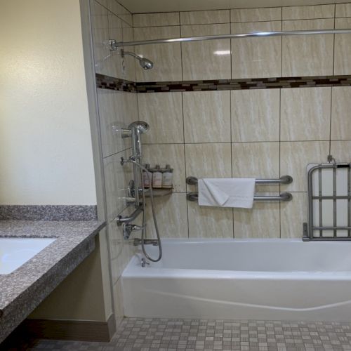 A hotel bathroom with a bathtub, shower fixtures, and neatly folded towels on racks.