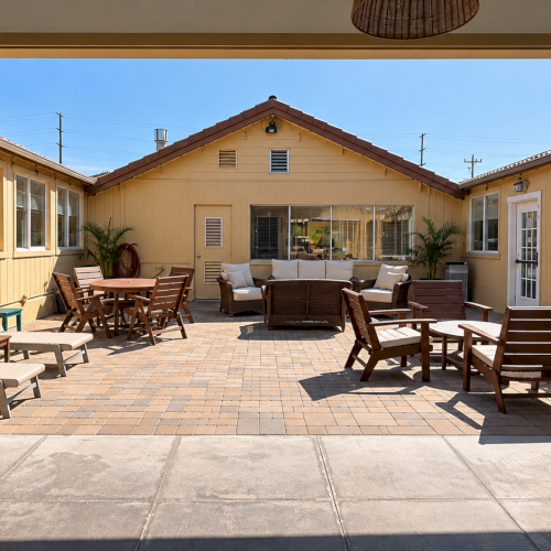 Sunny backyard patio with outdoor seating, a dining table, potted plants, and a central lounge area under a clear sky.